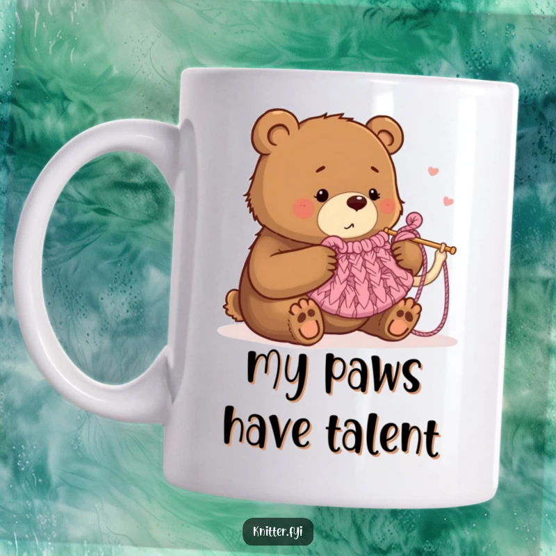 Funny mug showing a determined brown bear with oversized knitting needles trying to make a small tea cozy, conveying humor and effort.