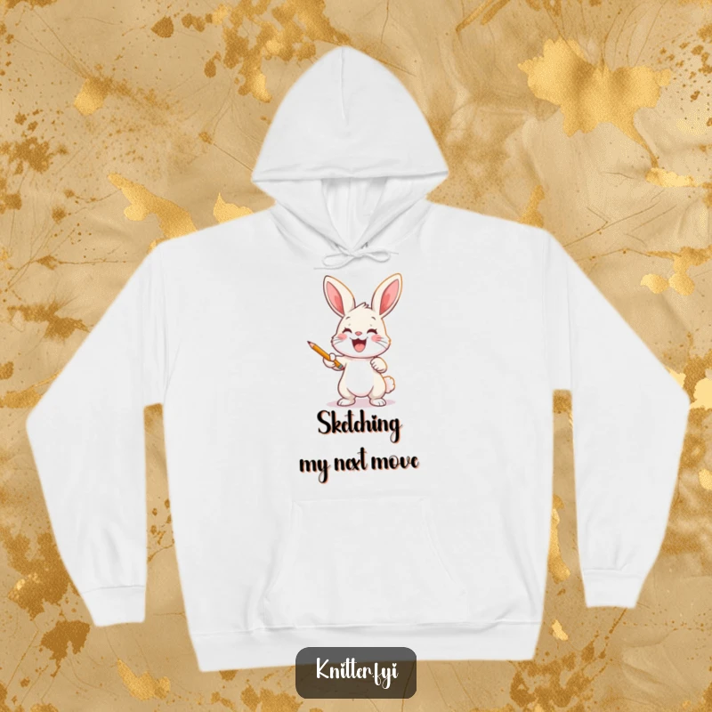 Funny bunny artist hoodie depicting a joyful rabbit casting a pattern onto fabric with a pencil, perfect for creators.