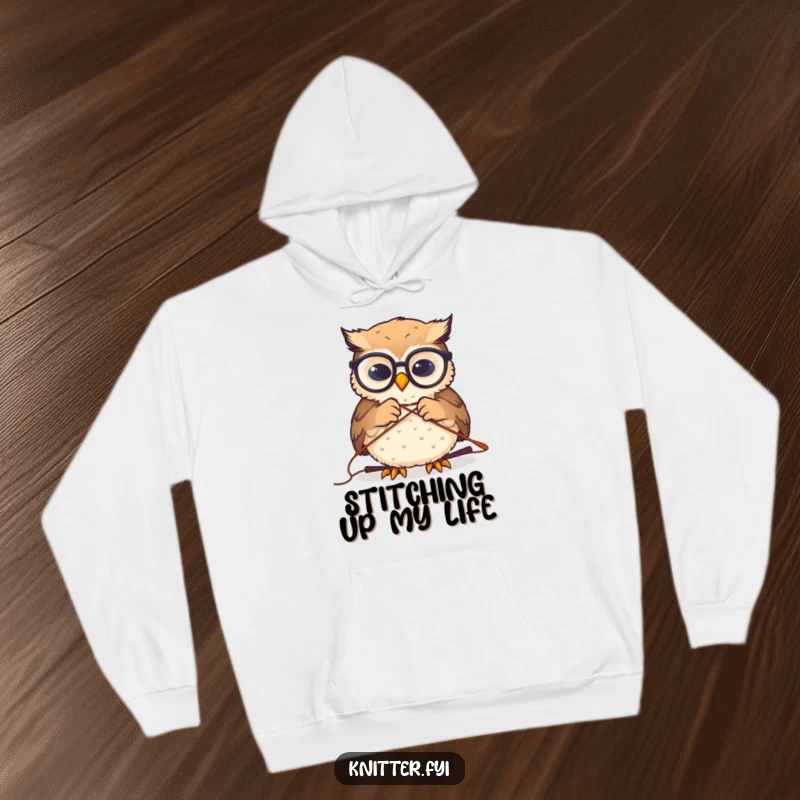 Funny hoodie depicts a miniature owl with glasses intently threading a large sewing needle, offering a humorous take on focused crafting.